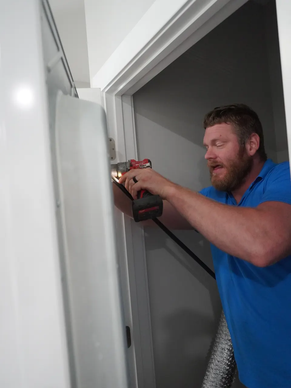 Nate working near a stacked washer and dryer unit during a service call