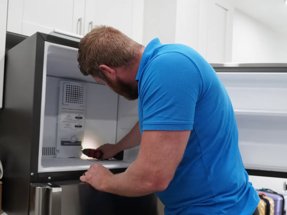 Technician inspecting a refrigerator's freezer compartment on an Indianapolis-area service call