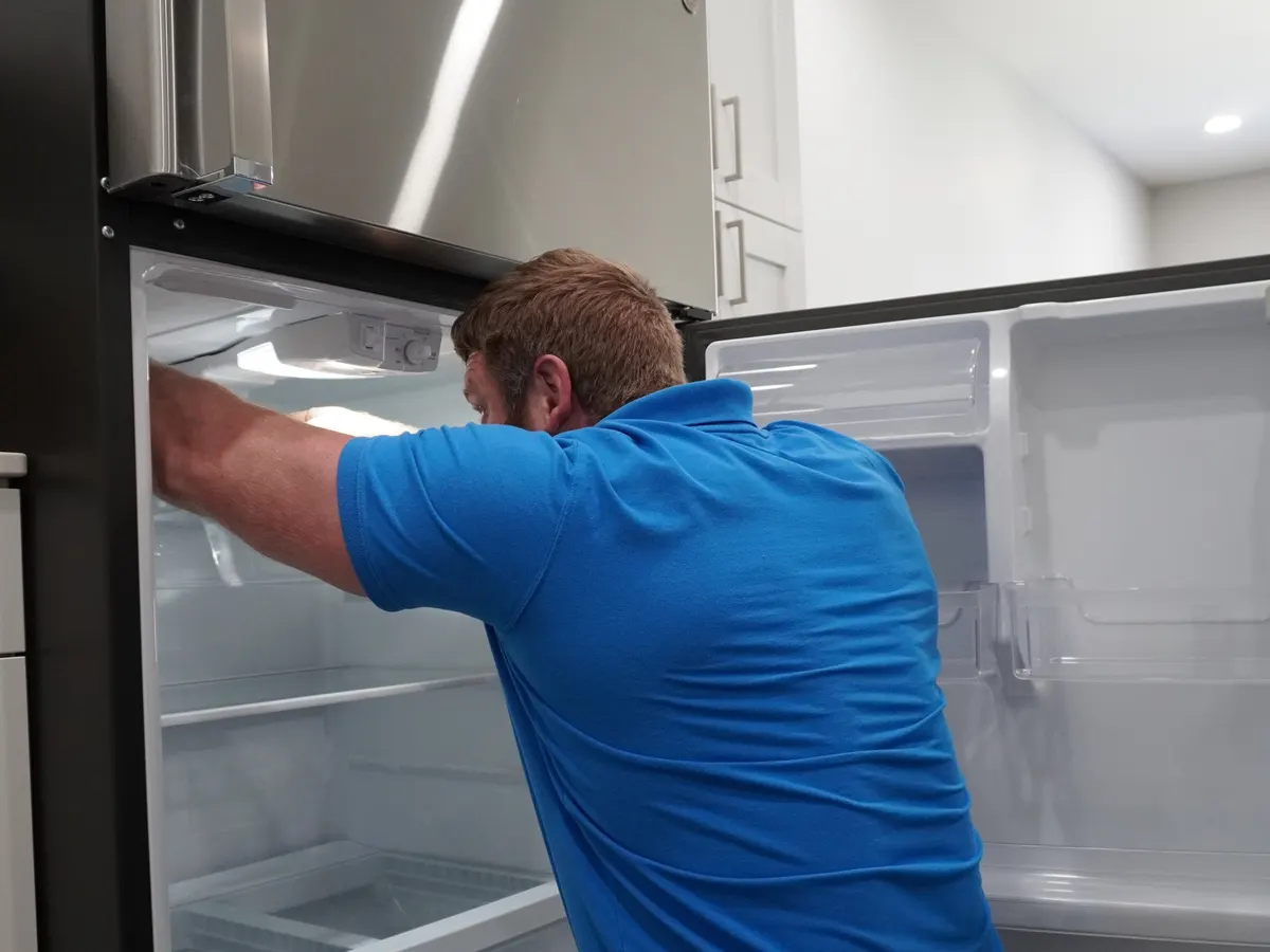 Technician inspecting a side-by-side refrigerator during a repair visit