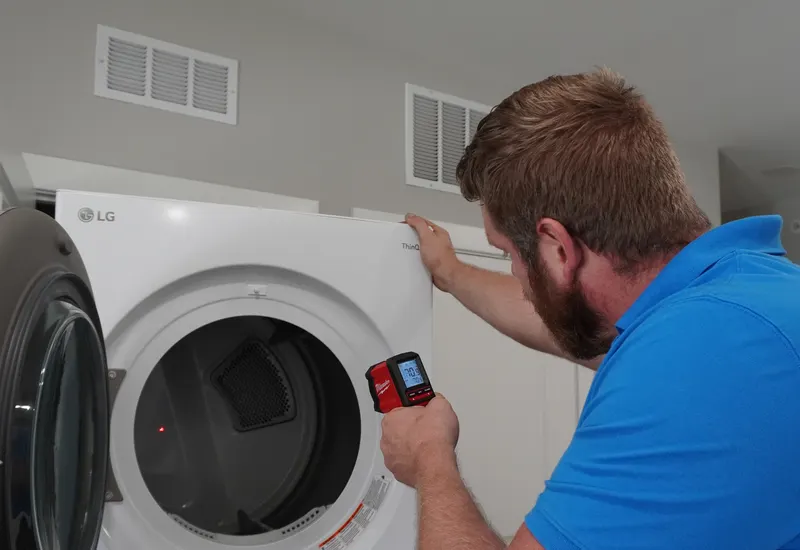 Technician testing a dryer's electronic control panel with a multimeter during a repair call