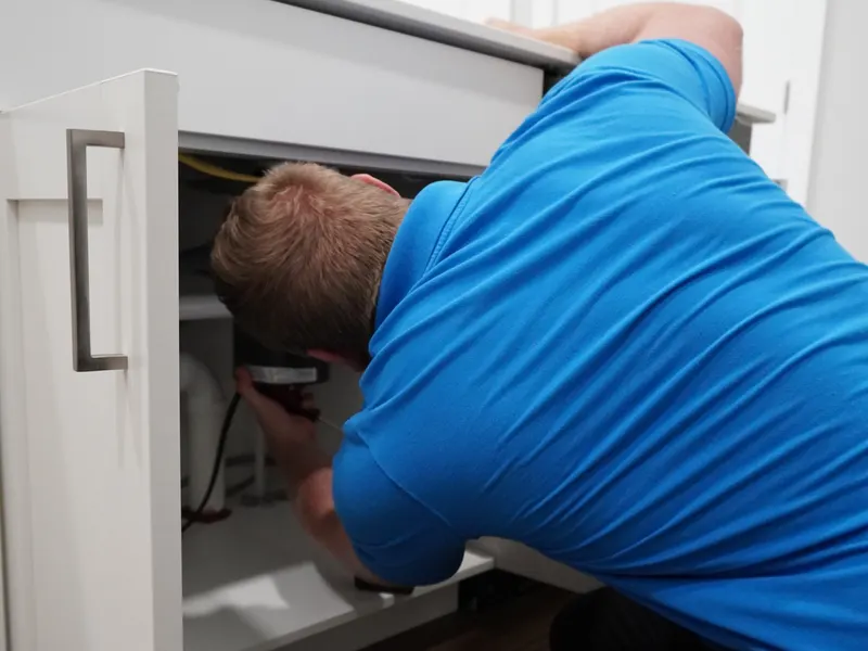 Garbage disposal unit accessed under the kitchen sink during a repair visit