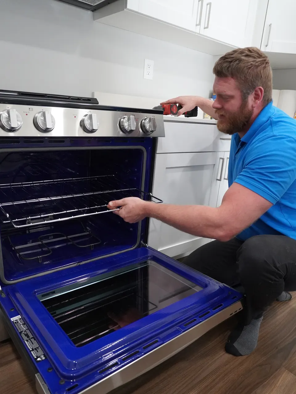Nate Baird, owner of Nate's Appliance Repair And HVAC, working on an oven during a repair call