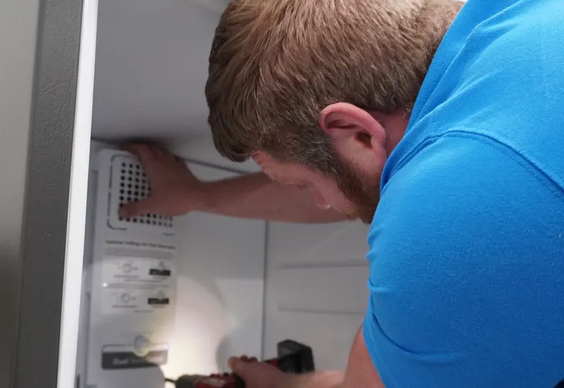 Technician checking the inside of a refrigerator during a repair visit on an Indianapolis-area service call