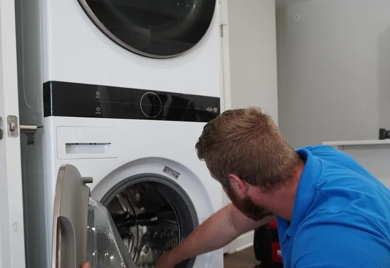 Technician working inside an open front-load washer drum during a repair visit